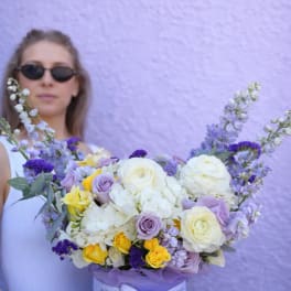 Lavender hatbox bouquet of white, purple, and yellow flowers