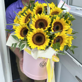 Bouquet of yellow sunflowers in a pink hatbox with a yellow ribbon