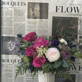 Pink and white mixed bouquet in a white vase with striped ribbon accents