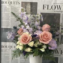 Pastel floral arrangement in a white vase with roses and lavender blooms