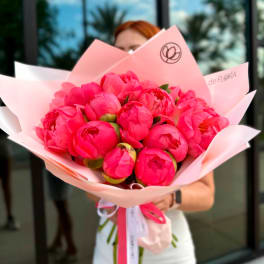 Bouquet of bright pink peonies wrapped in pale pink paper