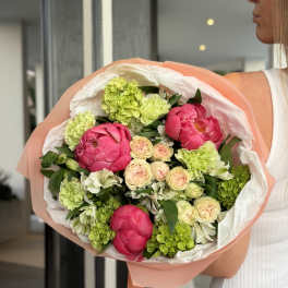 Bouquet of pink peonies and green hydrangeas wrapped in peach paper