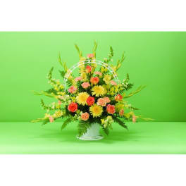 Mixed flower arrangement in a white basket with pink and yellow blooms