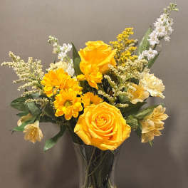Yellow roses and daisies arranged in a clear glass vase