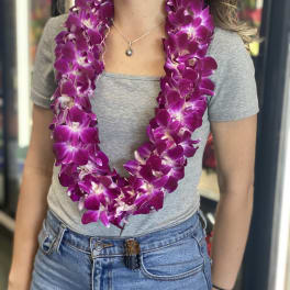 Woman wearing a purple orchid lei over a gray shirt