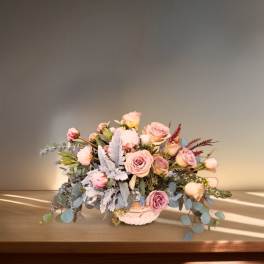 Low bouquet of pale pink roses in a white vase