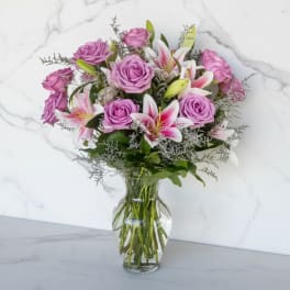 Pink roses and white lilies arranged in a clear glass vase