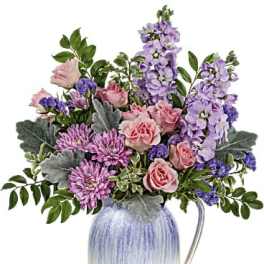 Pink and lavender flowers arranged in a ceramic pitcher vase