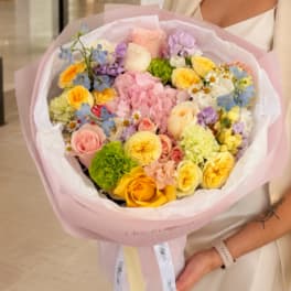 Pastel mixed bouquet with roses, carnations, and daisies wrapped in pink paper