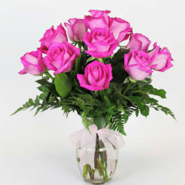 Pink roses in a clear glass vase with a white ribbon