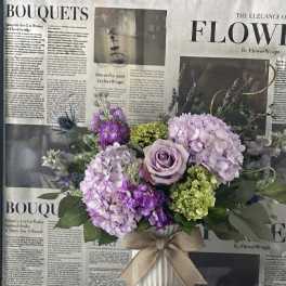 Lavender and purple bouquet in a white vase with a burlap bow