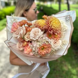 Bouquet of blush roses and peach chrysanthemums wrapped in white paper