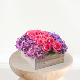Pink roses arranged with purple hydrangeas in a wooden box