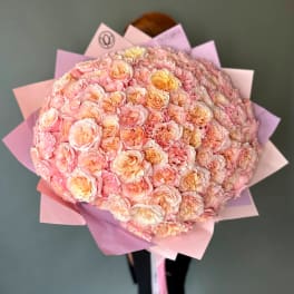 Large bouquet of pale pink and peach roses wrapped in pink paper