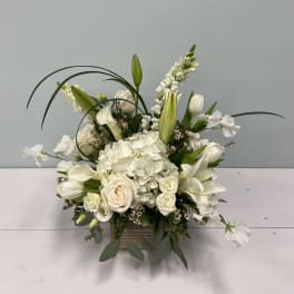 White floral arrangement with lilies, roses, and hydrangea in a square vase