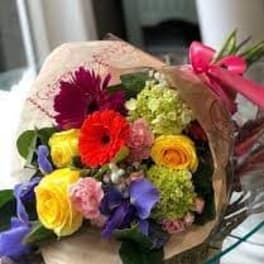 Bouquet of mixed colorful flowers wrapped in paper with a pink ribbon