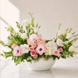 Pink and white floral arrangement in a white bowl vase