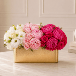 Pink and white flower arrangement in a gold rectangular box