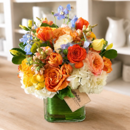 Colorful bouquet of mixed flowers in a clear square vase