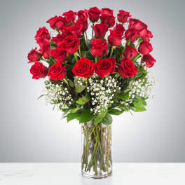 Tall bouquet of red roses with baby's breath in a clear glass vase