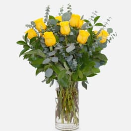 Yellow roses in a clear glass vase with eucalyptus