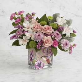 Pink roses and mixed blooms arranged in a square glass vase