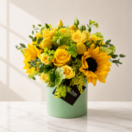 Yellow roses and sunflowers arranged in a mint green box
