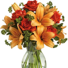 Orange lilies and red roses arranged in a clear glass vase.