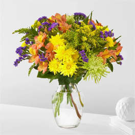 Bouquet of yellow, purple, and peach flowers in a clear glass vase