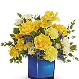 Yellow and white flower arrangement in a blue glass vase