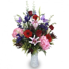 Mixed bouquet of lilies, roses, gerbera daisies, and hydrangeas in a glittery vase
