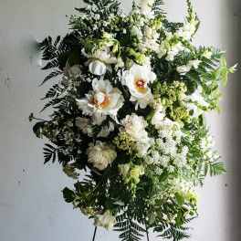 Large white floral standing spray with mixed greenery on an easel