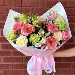 Bouquet of pink and cream flowers wrapped in pale paper with a ribbon