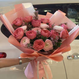 Pink rose and ranunculus bouquet wrapped in peach paper