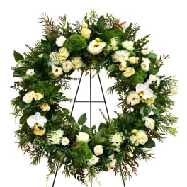 Large floral wreath with white roses and orchids on a black stand