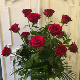Red roses arranged in a clear glass vase with greenery