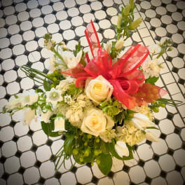White floral bouquet with roses and tulips, tied with a bright red ribbon
