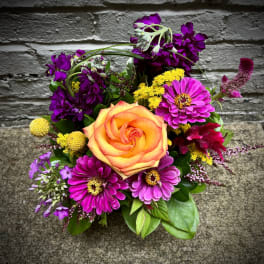Mixed bouquet with an orange rose and bright purple flowers
