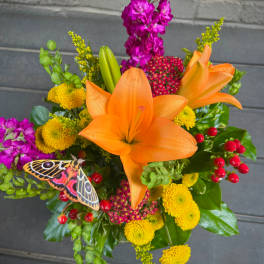 Bouquet of orange lilies, yellow mums, and purple flowers with a butterfly accent