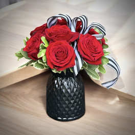 Red roses in a black vase with striped ribbon