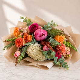 Mixed bouquet of roses, peonies, and hydrangea wrapped in kraft paper
