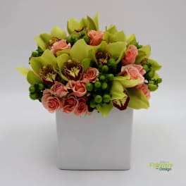 Bouquet of pink roses and green orchids in a white square vase