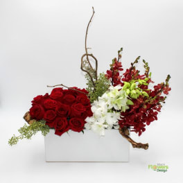 Red roses and white orchids arranged in a white rectangular vase