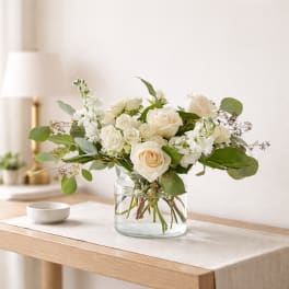 White roses and small white flowers in a clear glass vase