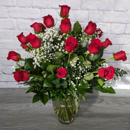 Red roses arranged in a clear glass vase with white baby's breath