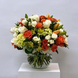 Bouquet of orange and white roses in a clear glass vase