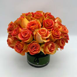Orange roses arranged in a round glass vase