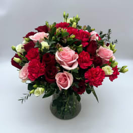 Bouquet of pink and red roses and carnations in a glass vase