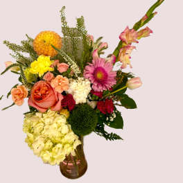 Mixed bouquet in a glass vase with pink, peach, yellow, and white flowers