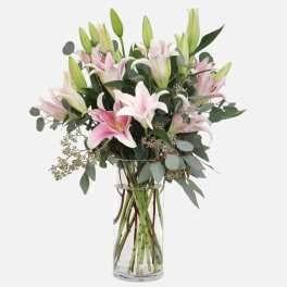 Bouquet of pink and white lilies in a clear glass vase